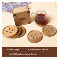 Delightful button-shaped wooden coasters made from natural mango wood, shown with a matching holder, textured glass mug, and gold spoon on a light fabric surface — thumbnail