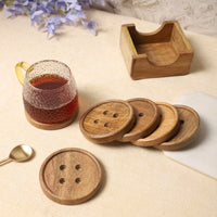 Wooden coasters with button-inspired designs and a matching holder, paired with a textured glass mug of tea and a golden spoon on a neutral tabletop — thumbnail
