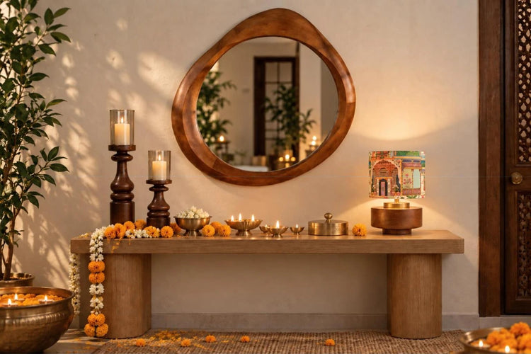 Oval asymmetric wooden mirror above a festive console with a lit Maharani table lamp, candle stands and diyas