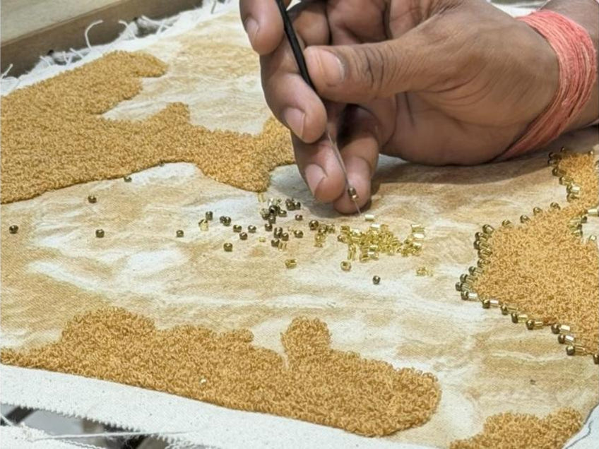An artisan doing adda work, setting gold beads by hand, in our studio